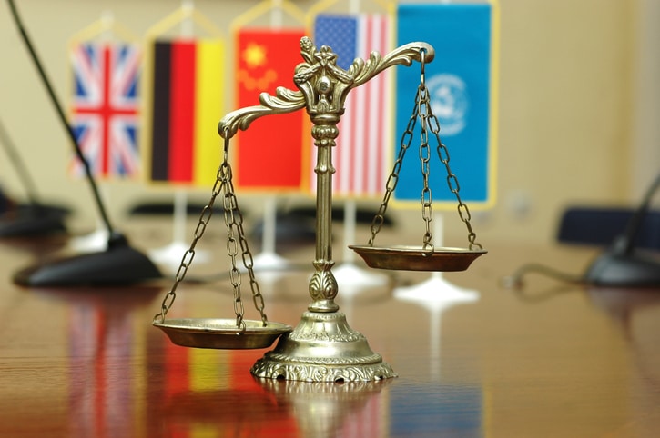 Decorative Scales of Justice with blurred National flag of different countries, concept of International Law and Order, focus on the scales