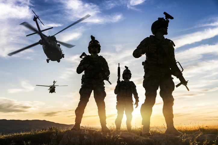 Squad of Three Fully Equipped and Armed Soldiers Standing on Hill  at sunset