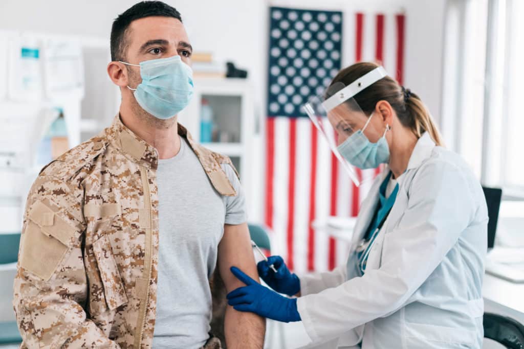 Nurse vaccinates a soldier with COVID-19 vaccine. Prevention and immunization from coronavirus infection