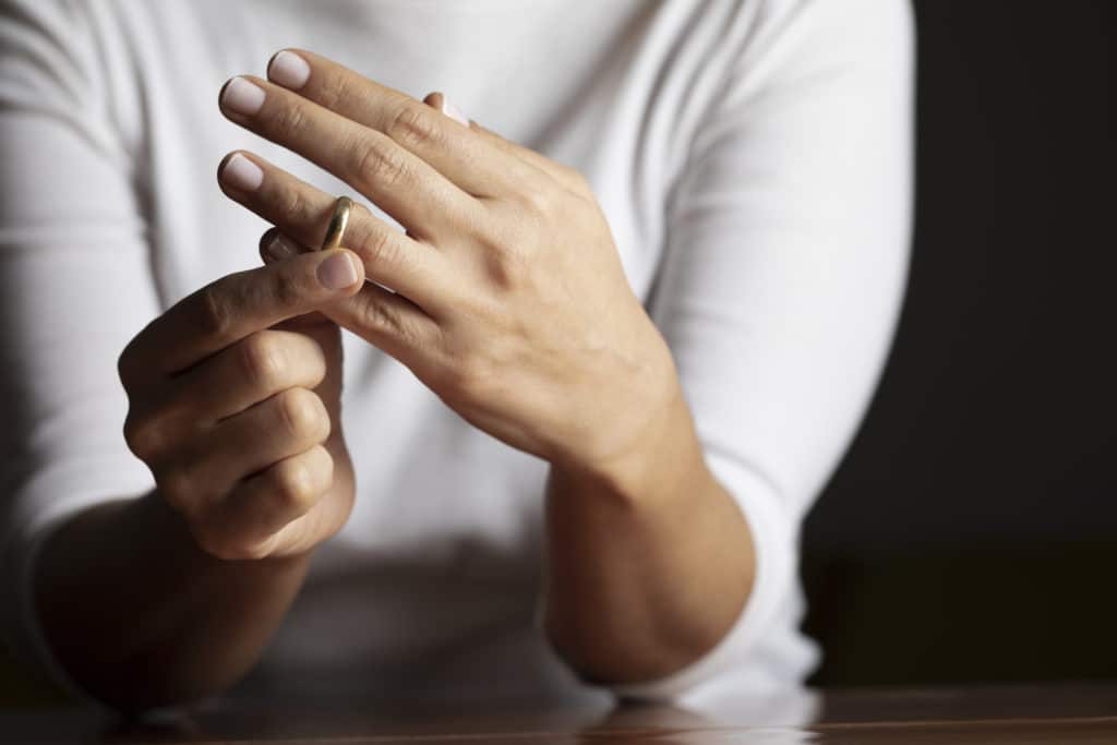 Hands of caucasian female who is about to taking off her wedding ring.