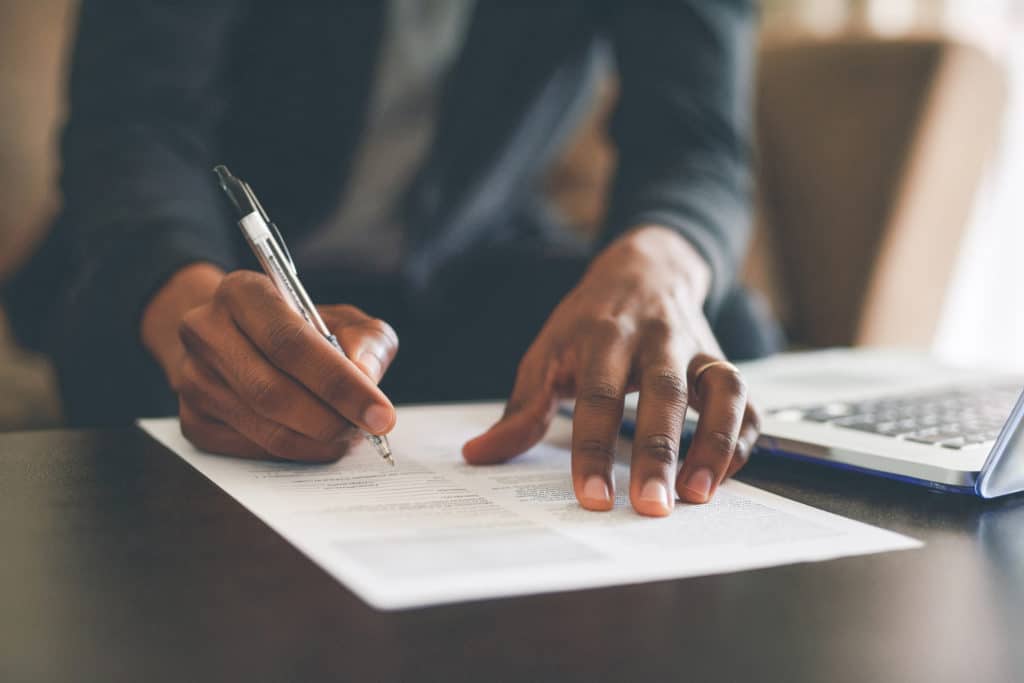 Cropped shot of an unrecognizable man filling out paperwork while doing his budget at home