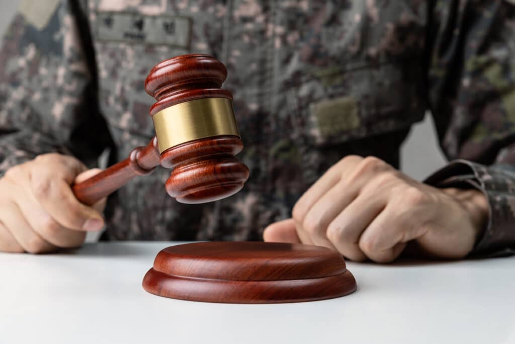 Military Law concept, Hand of soldier holding gavel at courtroom.