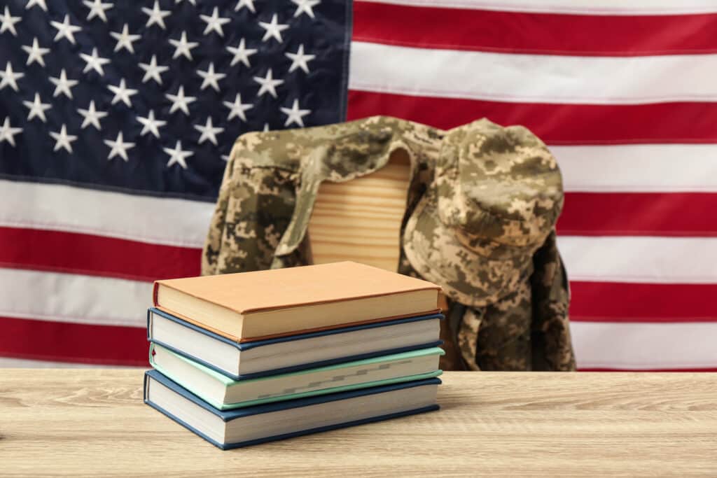 Books and soldier uniform near flag of United States. Military education