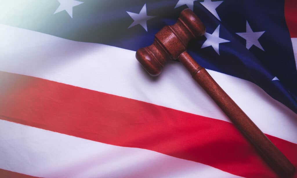 Justice in the USA. American Court. Sentencing the accused. The application of punishment to the guilty and the acquittal of the innocent. The jury in the courtroom and the judge. Hammer of the judge on the background of the usa flag.